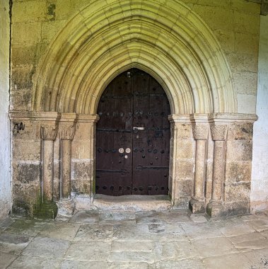 Eski İspanyol kilisesinde ahşap kapı ve sütunlarla süslü Gotik taş kapı..