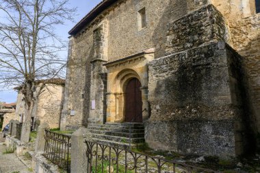 İspanya kırsalında çan kulesi ve Romanca kapısı olan ortaçağ taş kilisesi.