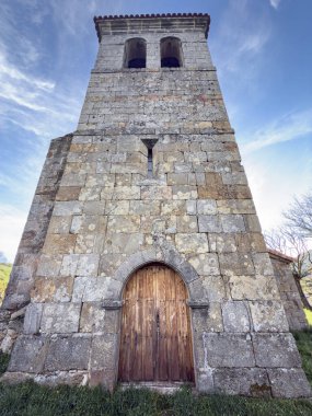 Ahşap kapılı ve çan kulesi olan taştan kilise kulesinin ön manzarası.