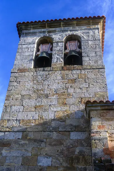 Ahşap kapılı ve çan kulesi olan taştan kilise kulesinin ön manzarası.