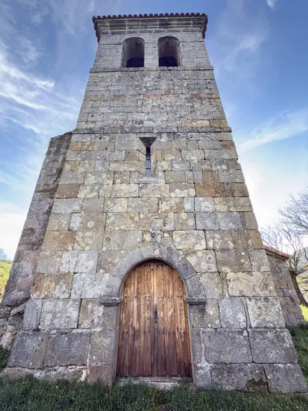 Ahşap kapılı ve çan kulesi olan taştan kilise kulesinin ön manzarası.