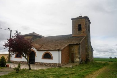 Çan kulesi olan San Andres 'in tuğla kilisesi Villarrobejo, Palencia' daki yeşil alanlar arasında geçiyor..
