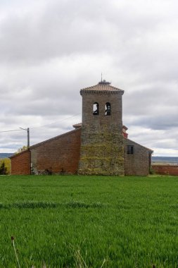 Çan kulesi olan San Andres 'in tuğla kilisesi Villarrobejo, Palencia' daki yeşil alanlar arasında geçiyor..