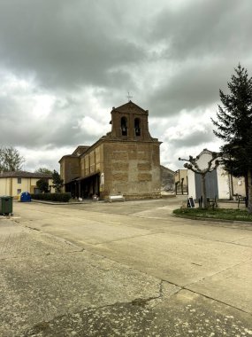 San Nicolas del Real Camino 'daki tuğla kilise çift çan kemeri ve bulutlu gökyüzü ile