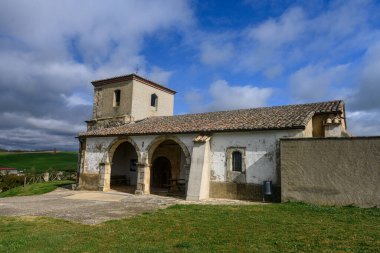 Olea de Boedo 'da çan kulesi ve taş kemerlerle boyanmış bir kilise.