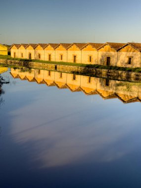 Tarihi depolar, Palencia 'daki Canal de Castilla rıhtımının durgun suyunda yansıtılıyor.