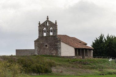 Dehesa de Romanos Palencia İspanya 'da kiremitli çatı, kemerli veranda ve çan geçidi olan ortaçağ taş kilisesi.