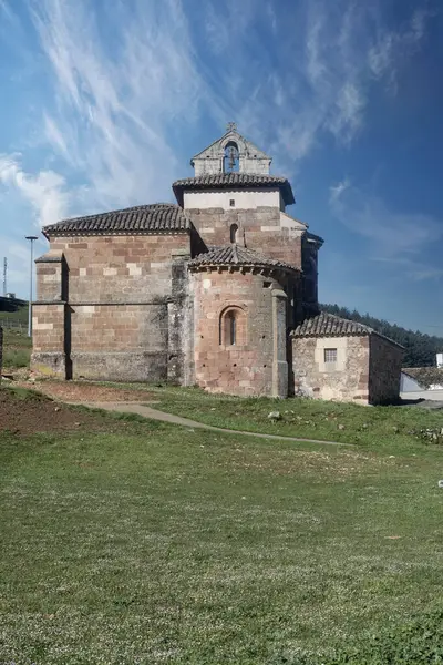 Nogales de Pisuerga 'da çift çan kemeri olan, otlar ve ışıkla çevrili Romanca kırsal kilise.