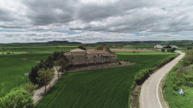 Palenzuela, Palencia, İspanya yakınlarındaki yeşil tarlalar arasında bir taş inzivasının insansız hava aracı görüntüsü