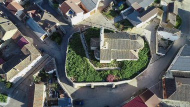 İspanyol köyündeki dairesel bir duvarla çevrili tarihi taştan kilisenin insansız hava aracı görüntüsü.