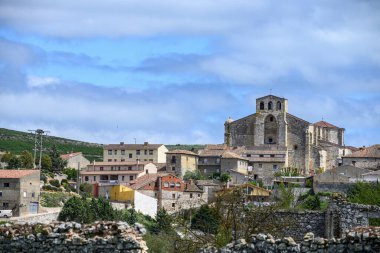 Palenzuela, Palencia 'daki San Juan Bautista Kilisesi' nin panoramik manzarası, Romanesk ve Gotik unsurların çatıların üzerinde yükseldiğini gösteriyor.