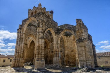 Gotik kilise kalıntıları, yüksek kemerler ve çan kulesi, kısmen çökmüş ama yine de heybetli.
