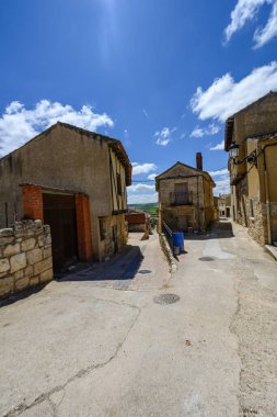 İspanya, Palenzuela 'da dar bir köy caddesi. Geleneksel evlerle dolu ve parlak bir yaz güneşinin altında parlak mavi bir gökyüzü altında yıkanmış.