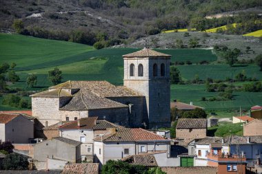 Kırsal taştan kilise ve çan kulesi köy çatıları ve manzaralı tepeler üzerinde yükseliyor.