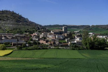 Valdecanas de Cerrato 'nun taştan kilise ve köy merkezi yeşil tarım arazileri ve tepelerle çevrili.