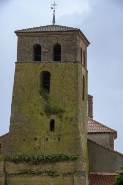 Kemerli açıkları ve kırsal bir köyde yosun kaplı tuğla duvarları olan uzun kır çan kulesi.