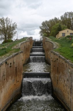 Fromista, Palencia 'daki Castilla Kanalı' nda akan su ile dört basamaklı eski bir taş kilit.