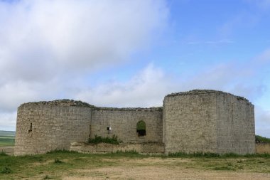 Palencia kırsalında yuvarlak kuleleri ve açık duvarları olan taş bir kale.