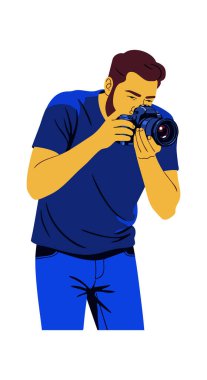 Resim, elinde kamera olan mavi elbiseli bir erkek fotoğrafçının sakin ve odaklanmış bir şekilde bir fotoğraf çekmeye odaklandığını gösteriyor..