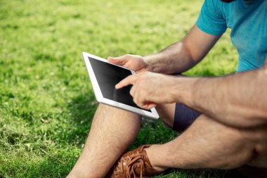 Parkta oturan ve modern dijital tablet, tablet pc dışında sosyal ağ kavramı kullanarak erkek blogger kullanarak genç hippi çocuk