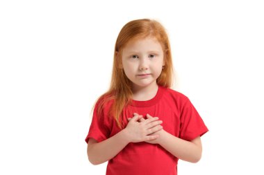 Stüdyoda kameraya bakarak poz veren neşeli beyaz kız portresi. Kırmızı tişörtlü kız avuç içlerini birbirine bastırıyor, yalvarıyor..