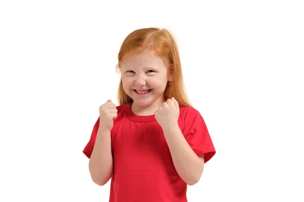 陽気少女は 彼女は 白の背景に隔離された彼女の拳を上げているので 興奮して見てください 赤いTシャツを着た赤毛の女の子の感情 — ストック写真
