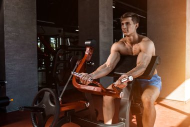Yük altındaki ellerin gergin kasları. Spor salonunda pazılar için egzersiz yapan bir adam. Simülatördeki kaslara çalış. Spor dergileri, posterler ve web siteleri için fotoğraflar. Güneş parlıyor