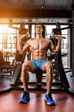 Yük altındaki ellerin gergin kasları. Spor salonunda pazılar için egzersiz yapan bir adam. Simülatördeki kaslara çalış. Spor dergileri, posterler ve web siteleri için fotoğraflar. Güneş parlıyor