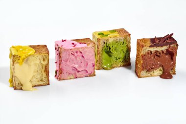 Puf böreği küp kruvasan kruvasan, kıtır kahverengi kabuk ve vanilya ve dut muhallebisi doldurma, şam fıstığı ve çikolata kreması beyaz arka planda izole edilmiş. Popüler fırında tatlılar