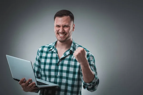 男のチェックTシャツのノートパソコンを見て 半分のターン ノートパソコンを開いて作業しています 感情だ スタジオ ウエストアップ プロフィール — ストック写真