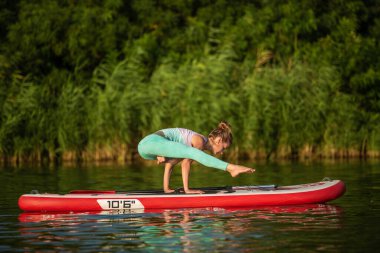 Genç kadın kürek kurulu Sup bir güzel göl veya nehir üzerinde ayağa yoga yapıyorsun. Sağlıklı bir yaşam tarzı kavramı. Spor. Yoga. Hobi