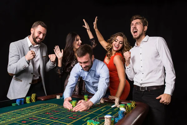一组年轻人在黑色背景的轮盘赌桌后 赢的球员 明亮的情绪 — 图库照片