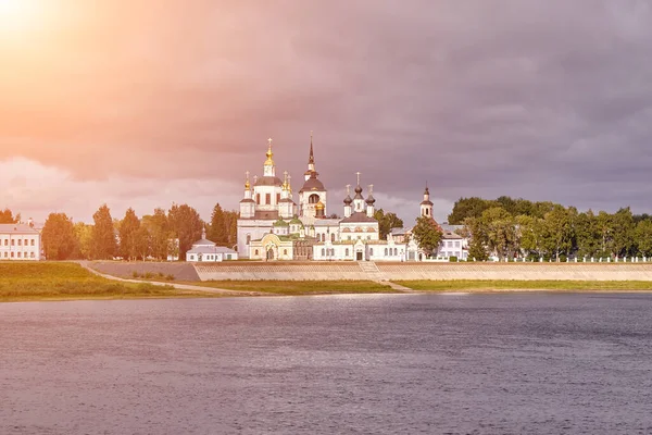 stock image A small church and the bell tower on the banks of the river, Russia, the village. Sun flare