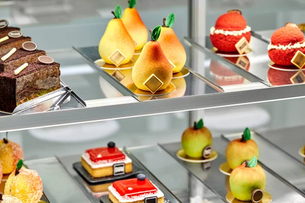 りんご 桃の形をしたカラフルなペストリー チョコレートケーキのスライス フルーツゼリーとベリーをトッピングした小さなチーズケーキが展示されています 作家菓子の概念 — ストック写真