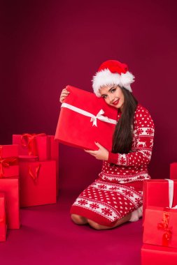 Genç beyaz kadın alışveriş torbaları ve Noel hediyeleriyle çevrili yerde oturuyor. Sıcak kışlık giysiler. Noel tatili.