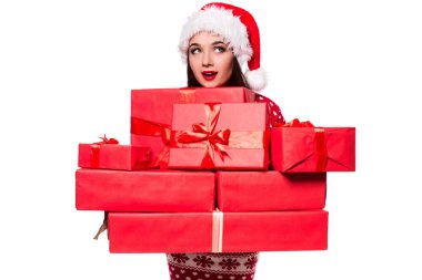 Sevinçten havalara uçmuş, elinde hediyeler tutan güzel bir dişi. Beyaz arka planda izole edilmiş Noel Baba şapkalı kadın.