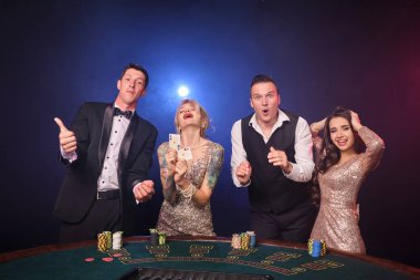 Bir grup zengin sınıf arkadaşı kumarhanede poker oynuyor. Gençler büyük bir galibiyet için bahis oynuyorlar. Masada kırmızı ve mavi arka farlara karşı duran kameraya bakıyorlar.