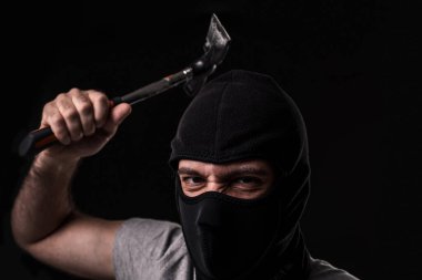 Tişörtlü ve çekiçli kar maskeli bir suçlu. Stüdyodaki siyah arka planda. Haydut ve hırsız.