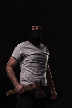 Siyah arka planda baltası olan siyah maskeli bir haydut. Baltalı maskeli adam.