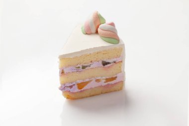 Hafif mascarpone kremalı yumuşak sünger keki ve beyaz arka planda renkli şekerlerle süslenmiş taze meyve parçaları.