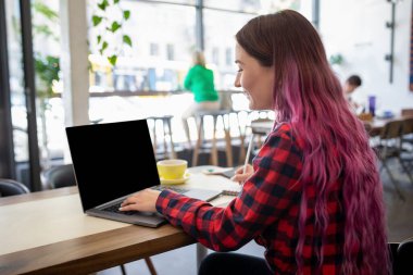 Kız öğrencinin öğrenme online yolu ile dizüstü onu ders önce kadeh arka. Kadın defter ile kopya alanı metin veya reklam içeriği, tahta masada oturan için boş ekran ile yazarak