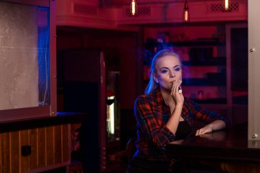 Kafesteki tişörtlü güzel bir kadın Vape Bar 'da elektronik sigara içiyor. Vestiyer..