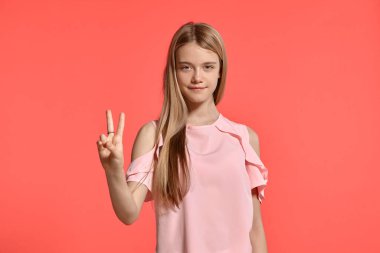 Studio portrait of an attractive blonde young lady with a long hair, in a rosy t-shirt, standing against a pink background in various poses. She expresses different emotions posing right in front of