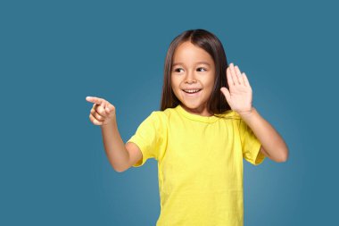 Cute girl shows her finger on blue background