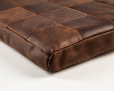 Closeup of soft meditation cushion for knee and leg comfort made from brown genuine leather patches. Handmade accessory for interior design