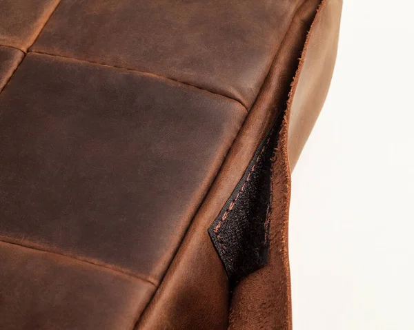 Closeup of decorative seat cushion made of patches of brown leather with hook-and-loop fastener for comfort and stylish home interior design. Artisanal genuine leather products