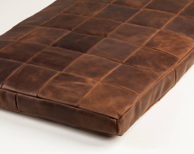 Decorative soft seat cushion upholstered by brown leather patches for comfort and stylish home interior design. Artisanal genuine leather products