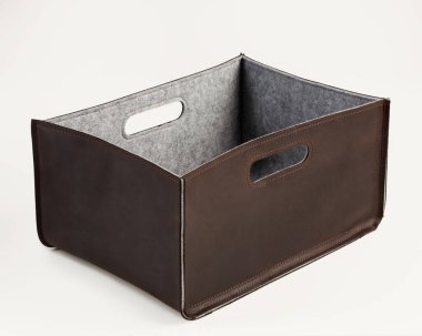 Brown leather bin lined with gray felt and slotted handles for comfortable storage and carrying of home and office items. Artisanal interior accessory