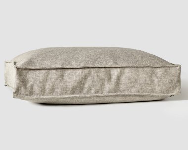 Soft plump pillow for sofa with cover of natural plain color gray fabric finished with piping for stylish and cozy interior design. Handmade furnishing accessory