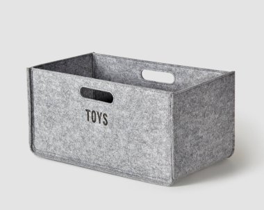Handcrafted gray felt box with inscription on side and slotted handles for storing toys. Stylish accessory to organize home space